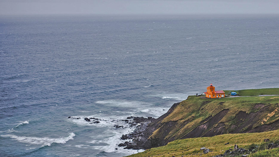 An orange lighthouse by the sea